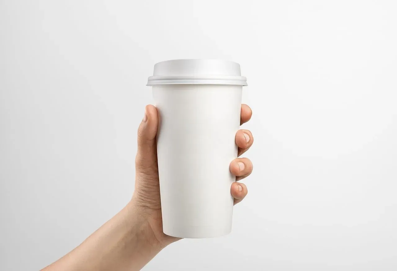 Close-up of a reusable insulated tumbler and coffee cup on a minimal kitchen surface